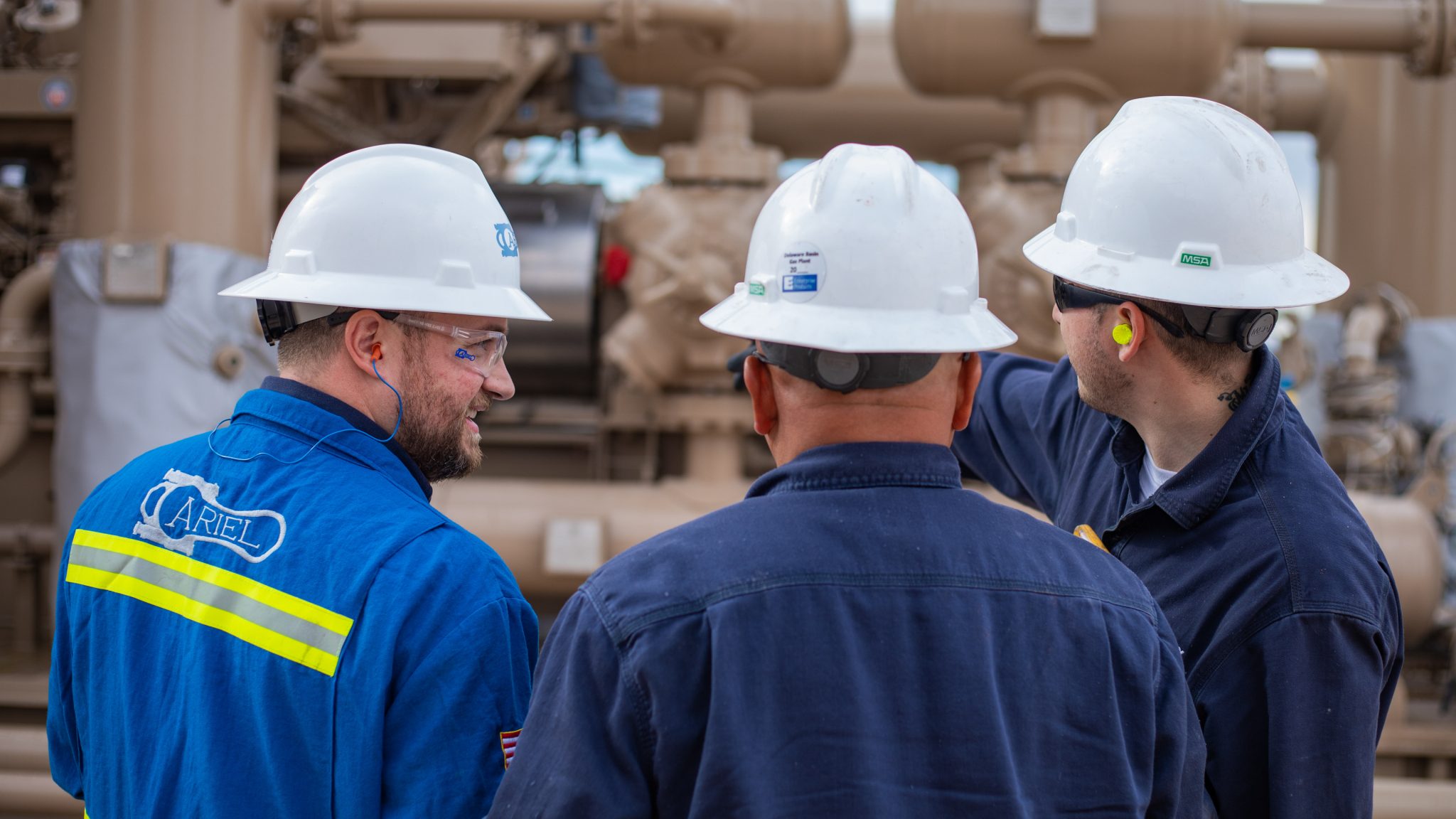 Two mechanics talking to an Ariel technician an the Sandero compressor station in New Mexico
