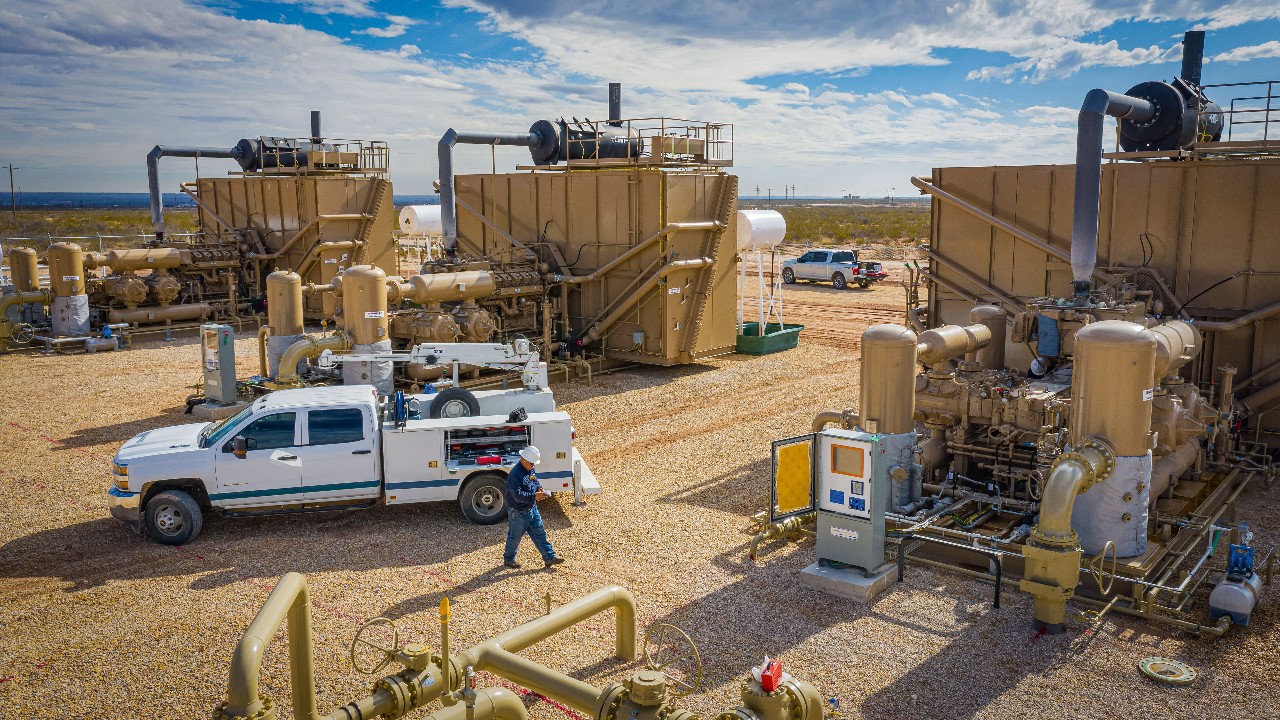 A mechanic walking from his truck to a compressor package at a compressor station in New Mexico